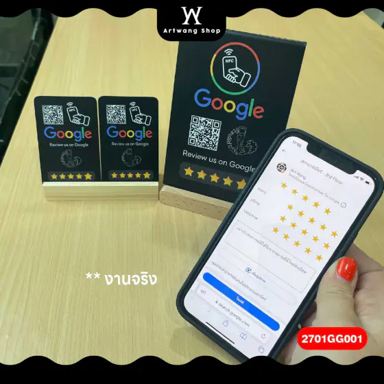 ป้ายและการ์ดสีดำวางบนโต๊ะ ข้างมือถือที่เปิดหน้าให้ดาวรีวิว Google